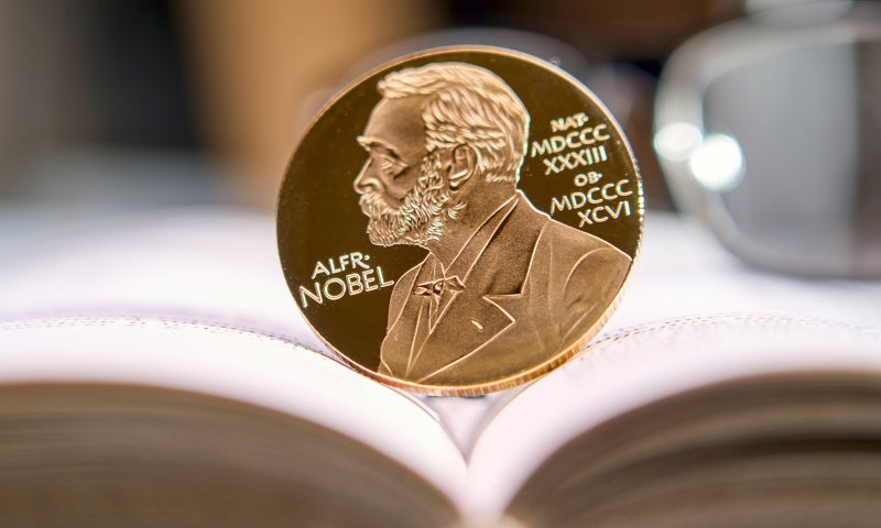 Photo of Nobel Prize medal resting on the pages of an open book.