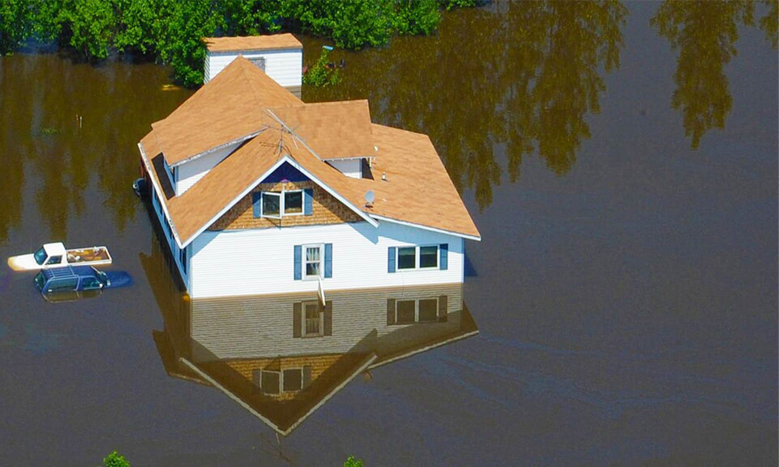 An aerial photo of a house nearly completely underwater from a flood.